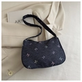 Gros plan du sac porté épaule en denim bleu avec nœuds colorés sur un blazer beige - Noir
