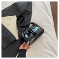 Dettaglio della borsa in vernice lucida con occhielli dorati e laccetto decorativo - Nero