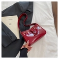Dettaglio di una borsa a spalla in pelle verniciata rosso scuro con coulisse eleganti - Rosso