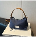 Detalle del bolso de mezclilla azul oscuro con asas de cuero marrón y una etiqueta - Estilo básico / Marrón Denim