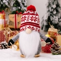 Christmas gonk gnome with red snowflake knit hat and wooden skis on snow background - Christmas Knitted Hat Sled Gnome Male Style