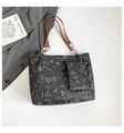 Detalle de bolso tote negro con asa de cuero marrón y cadena plateada con neceser interno - Negro