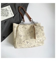 Detalle de un set de bolso tote con estampado de logo, estuche y acentos de cadena de metal - Blanco