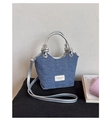 Detalle del bolso tote de mezclilla azul con asa trenzada plateada y etiqueta de cuero - Plateado