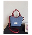 Detalle del bolso tote de mezclilla azul con asas de cuero rojo y parche con logo - Rojo