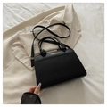 Dettaglio della borsa in pelle nera con manico annodato e logo dorato su trama minimale - Nero