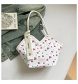 Close-up van witte bucket bag met kersenprint en brede schouderband in een lifestyle setting - Witte Kers
