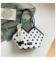 Detail van witte stippen bucket bag met V-vormige top en geweven handgrepen met merknaam - Witte Stippen
