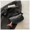 Detail of black crossbody bag with golden metal bow accent and wide shoulder strap - Black
