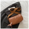 Close-up of caramel brown leather handbag with gold bow clasp and wide strap - Brown