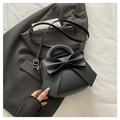 Close-up of a black leather handbag featuring a large bow and gold metal buckle hardware - Black