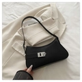Detalle de bolso de hombro tipo media luna negro con hebilla plateada sobre fondo beige - Negro