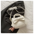 Detail of elegant cream handbag featuring a large bow and gold hardware accents - White
