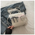 Detalle de mochila blanca con encaje y lazos de cuadros sobre cama blanca - Blanco