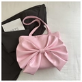 Pink tote bag detail featuring large bow design and matte leather texture on fabric background - Pink