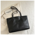 Detail der schwarzen Tote-Bag aus Kunstleder mit Narbung auf beigem Blazer-Hintergrund - Schwarz