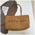 Dettaglio di una borsa tote in pelle scamosciata marrone con testo nero e un blazer - Giallo