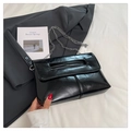 Detail of black glossy leather handbag featuring unique cutout handle and metal chain strap - Black