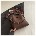 Detail of dark brown lychee textured leather bucket bag with jacquard strap and gold chain - Coffee
