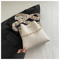 Close-up of off-white bucket bag with pebble leather texture and golden chain strap - White