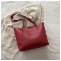 Detalle de bolso tote de cuero burdeos con texto sobre fondo de chaqueta beige liso - Rojo