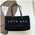 Borsa tote minimalista in pelle scamosciata nera con scritta TOTE BAG bianca e manici - Nero