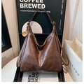 Macro detail of caramel brown leather tote bag with fine stitching and metal charm - With Pendant / Coffee