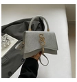 Dettaglio della borsa argento glitterata con base curva e logo dorato con nappa - Argento