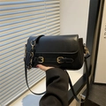 Chique zwarte crossbody tas met gouden gespen en acryl ketting op leer textuur - Zwart