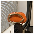 Detail of orange glossy mini bag with large gold C-handle and fine metal chain strap - Orange