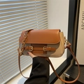 Modieuze tweekleurige schoudertas met bruine flap en beige body in de hand gehouden - Bruin