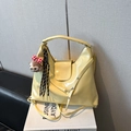 Detail of yellow glossy tote bag featuring brand logo engraving and cute bear charm - Yellow