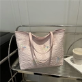 Pink tote bag with butterfly embroidery and quilted texture on a metal shelf display - Pink