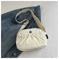 Bolso bandolera beige plisado en tela suave con correa ajustable sobre fondo denim - Blanco