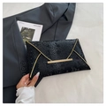 Dettaglio della pochette a busta nera con trama a serpente e bordo in metallo dorato - Nero
