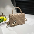 Chic beige crossbody bag with quilted texture and metal lock on a lifestyle setup - Khaki