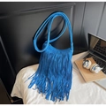 Royal blue faux suede crossbody bag with long tassels and matching strap on a desk - Blue