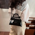 Sac cabas noir brillant avec breloque cheval, porté par un mannequin en intérieur chic - Noir Avec Pendentif
