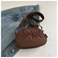 Chic brown pleated crossbody bag with metal logo on denim jacket background - Brown