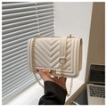 Close-up of white quilted crossbody bag with V-shaped stitching and gold chain strap - White