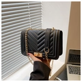Close-up of black quilted shoulder bag with gold chain strap and metal swivel lock detail - Black