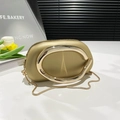 Elegante champagnerfarbene Clutch mit ovalem Goldgriff und Kette auf weißem Tisch - Gold