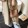 Niche bucket bag in brown pebble leather with top handle and shoulder strap for commute - Brown