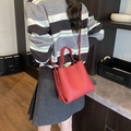 Vibrant red pebbled leather bucket bag with top handle and crossbody strap style - Red