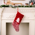 Gestrickter roter Weihnachtsstrumpf mit weißem Baummuster an einem weißen Kamin - Jenny J. Baum