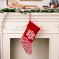 Roter gestrickter Weihnachtssocken mit weißem Schneeflockenmuster an weißem Kamin hängend - Schneeflocke