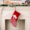 Rote gestrickte Weihnachtssocke mit weißem Hausmuster an einem weißen Kamin aufgehängt - Haus