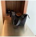Detalle de la correa ancha y hebilla de metal en el bolso bandolera negro con textura - Negro