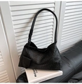 Detail einer schwarzen geflochtenen Hobo-Tasche mit Knotengurt auf schwarzem Sofa - Schwarz