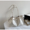 Close-up of minimalist beige leather tote bag with thin straps on a soft white surface - Off White